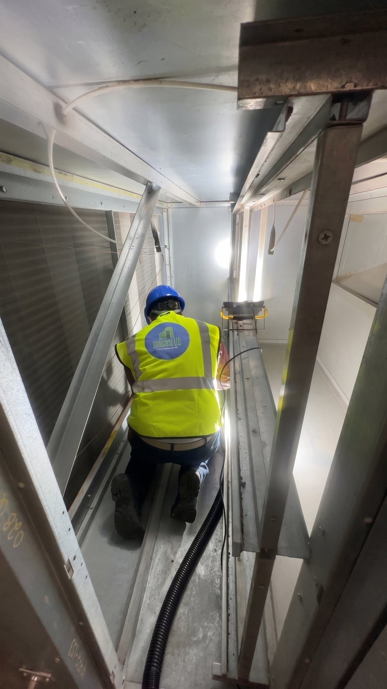 Urbacons technician working inside an air handling unit, company logo on the back of the vest