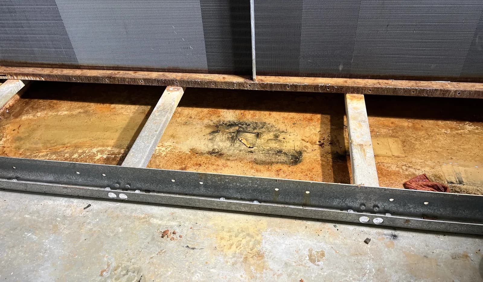A condensate pan with corrosion, before work