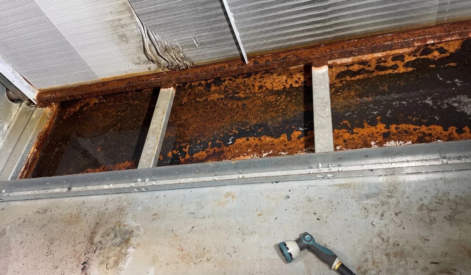 Condensate drain pan run showing heavy corrosion before restoration